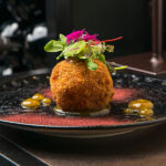 Rice, potato, and mussel arancino with yellow datterino tomato ketchup