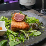 Tuna loin in panko crust, mixed salad and red bell pepper sauce with orange